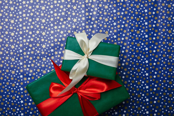 верхний вид завернутых новогодних подарков с лентами на оберточной бумаге с узором из звезд
