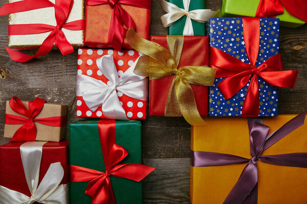 flat lay with christmas presents wrapped in different wrapping papers with ribbons on wooden surface