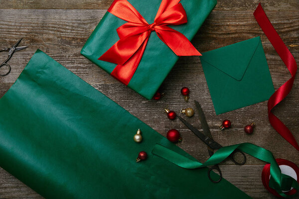 top view of christmas toys, wrapped present with ribbon and blank envelope for greeting card on wooden background