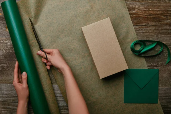 ギフトやエンベロープを持つ木製の表面に女性切断包装紙ハサミの部分ビュー — ストック写真