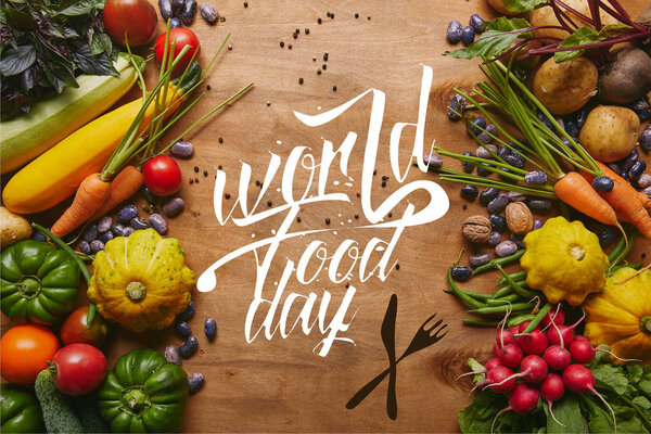 Frame of healthy food vegetables and beans on wooden table with "world food day" lettering