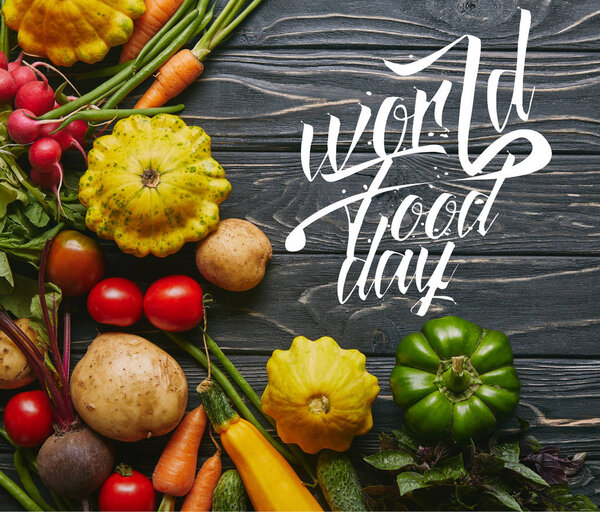 Organic raw vegetables on dark wooden table with "world food day" lettering