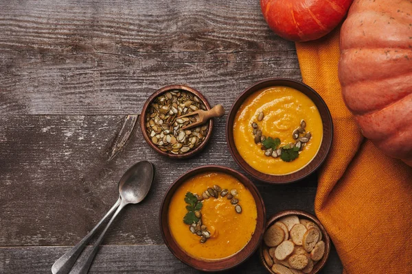 Schüsseln Mit Kürbissuppe Zwieback Löffeln Kürbiskernen Und Frischen Kürbissen Auf — Stockfoto