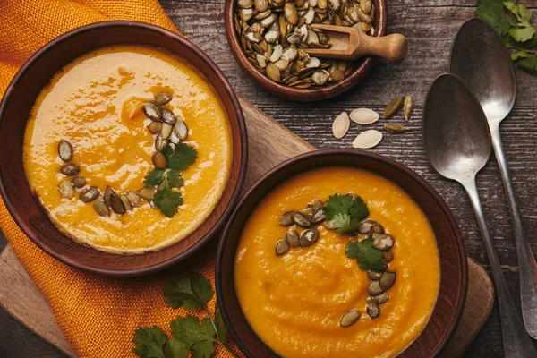 Top View Bowls Tasty Pumpkin Soup Spoons Pumpkin Seeds Wooden — Stock Photo, Image