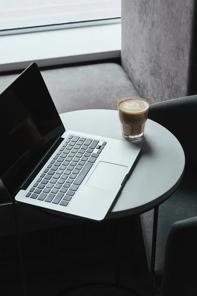 咖啡桌上有空白屏幕的笔记本电脑和咖啡杯卡布奇诺 — 免费的图库照片