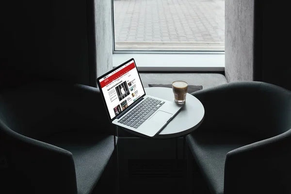 Bbc のニュース サイトとカフェでテーブルの上のコーヒー カップとノート パソコン — ストック写真