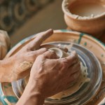 Närbild bild av mannen händerna arbetar på keramik hjul på verkstad