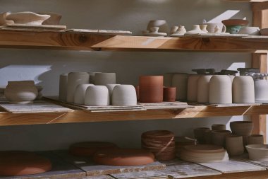 ceramic bowls and dishes on wooden shelves at pottery studio clipart