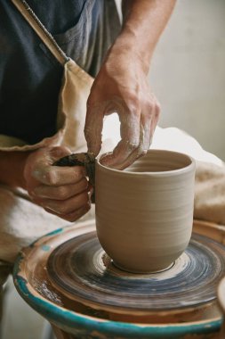 partial view of male craftsman working on potters wheel at pottery studio clipart