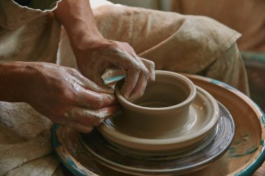 partial view of male craftsman working on potters wheel at pottery studio clipart
