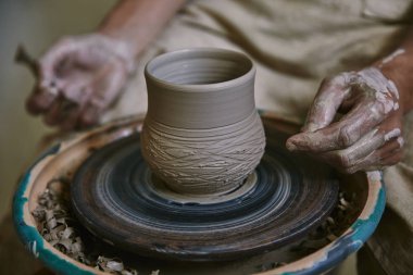 cropped image of male craftsman working on potters wheel at workshop clipart