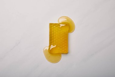 top view of handmade soap in shape of honeycomb poured with honey on white marble surface clipart