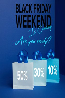 close up view of paper shopping bags arranged on blue with black friday weekend is coming are you ready? clipart
