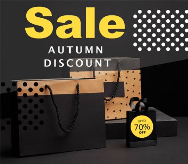 close up view of shopping bags arranged on black background with autumn sale discount with 70 percents clipart