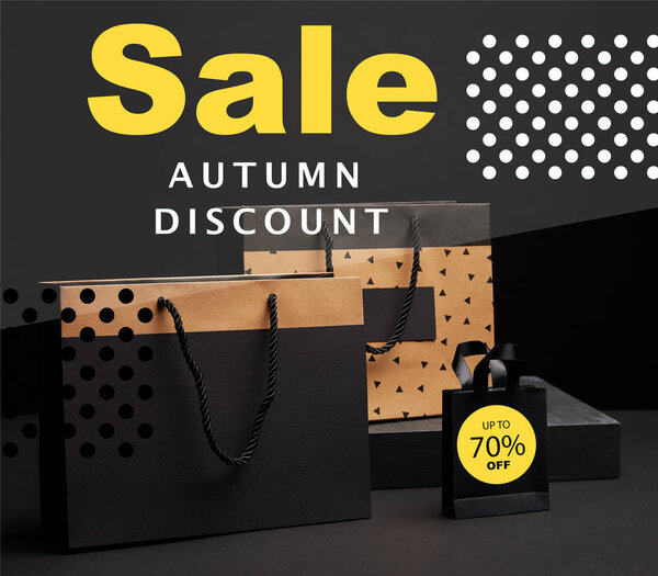 close up view of shopping bags arranged on black background with autumn sale discount with 70 percents