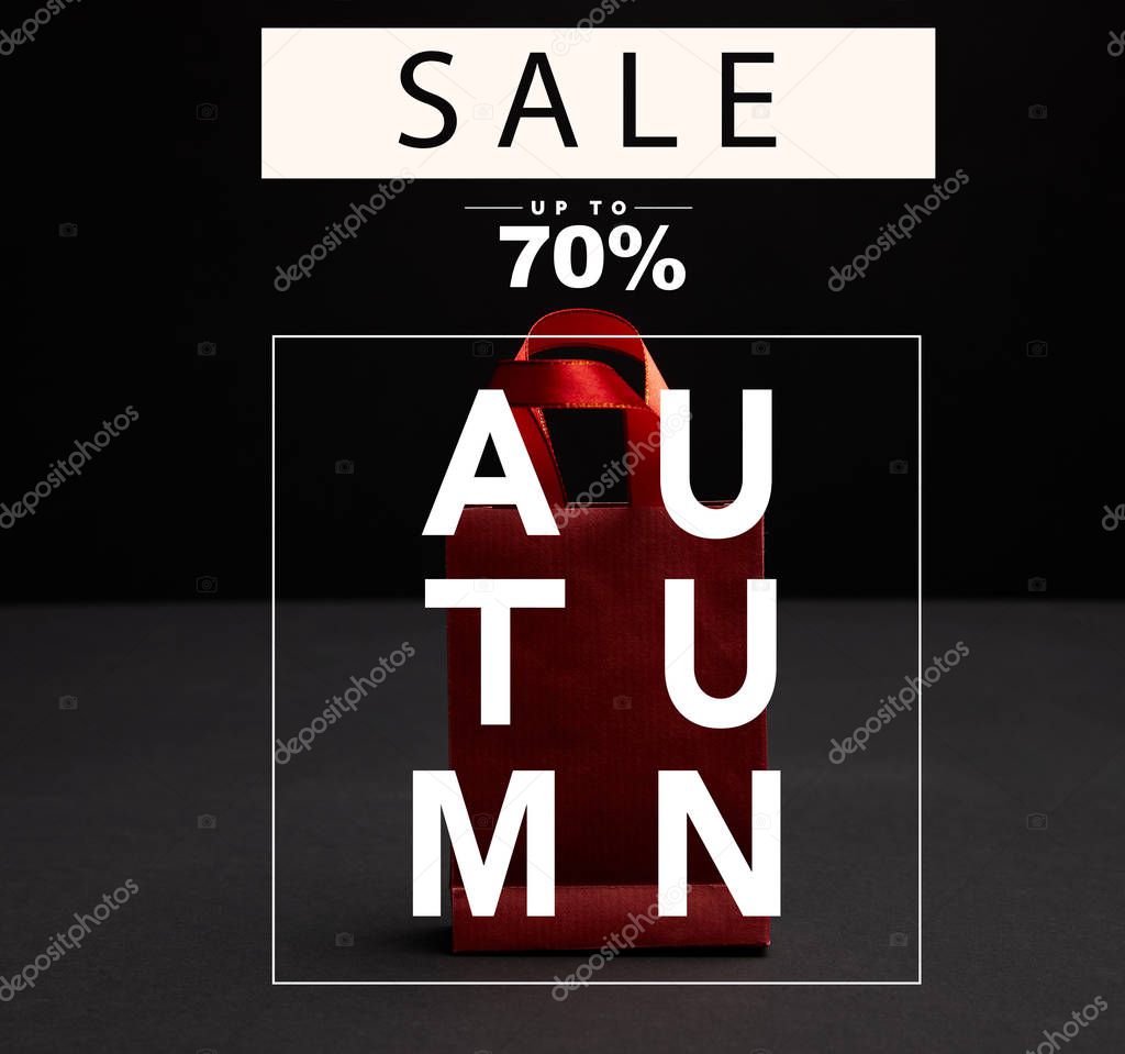 close up view of red paper shopping bag on black backdrop with autumn sale, 70 percents discount