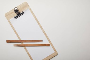 elevated view of blank menu and chopsticks on white surface, minimalistic concept  clipart