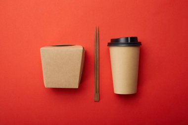 flat lay with chopsticks, noodle box and disposable cup of coffee on red surface, minimalistic concept  clipart