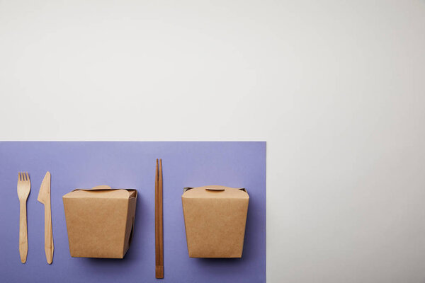 top view of noodle boxes, chopsticks and disposable fork with knife on purple 