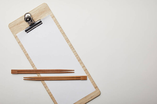 elevated view of blank menu and chopsticks on white surface, minimalistic concept 