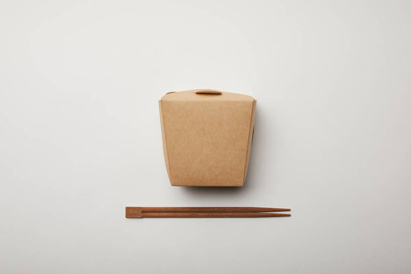 elevated view of arranged chopsticks and noodle box on white surface, minimalistic concept 