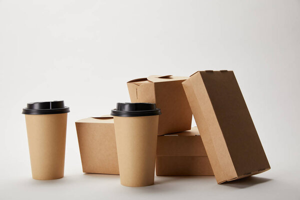 disposable coffee cups and cardboard food boxes on white