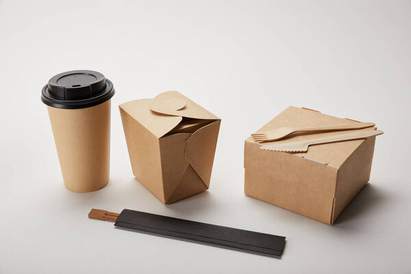disposable fork with knife, paper coffee cup, food boxes and chopsticks on white 