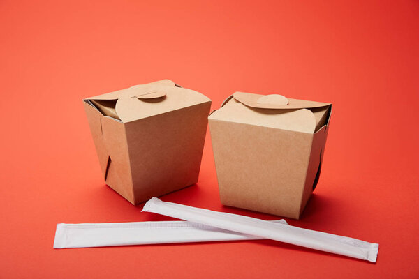 close up view of chopsticks and noodle boxes on red, minimalistic concept 