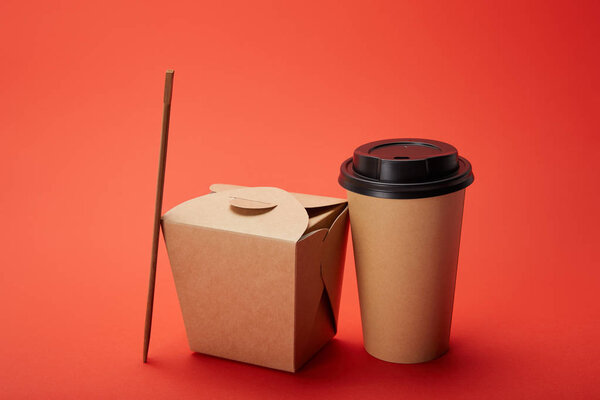 noodle box, paper cup of coffee with chopsticks on red, minimalistic concept