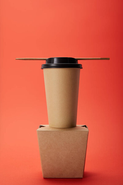 arranged noodle box, paper cup of coffee with chopsticks on red, minimalistic concept