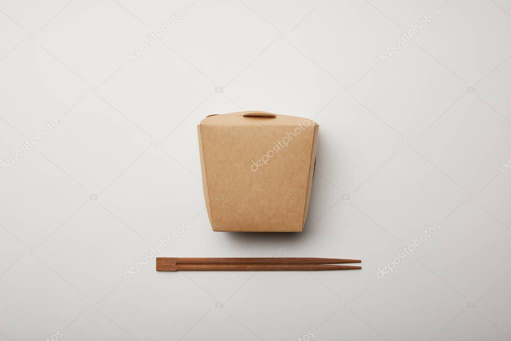 elevated view of arranged chopsticks and noodle box on white surface, minimalistic concept 