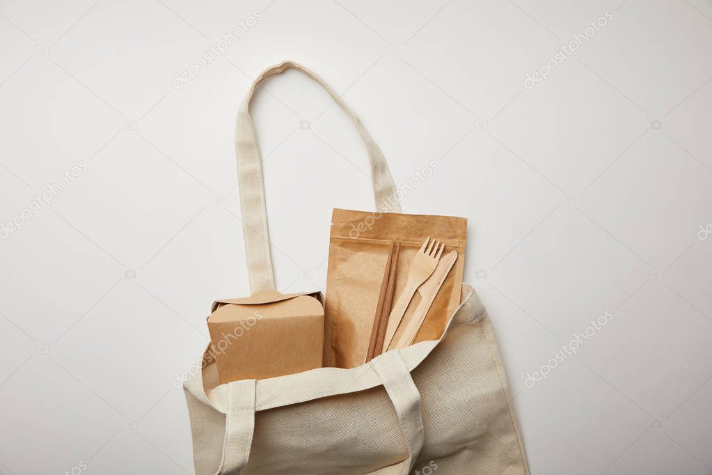 top view of cotton bag with noodle box, chopsticks and disposable forks with knives on white surface