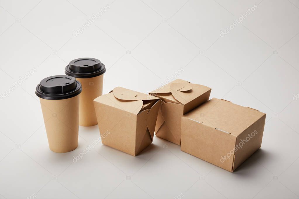 close up view of paper coffee cups and cardboard food boxes on white
