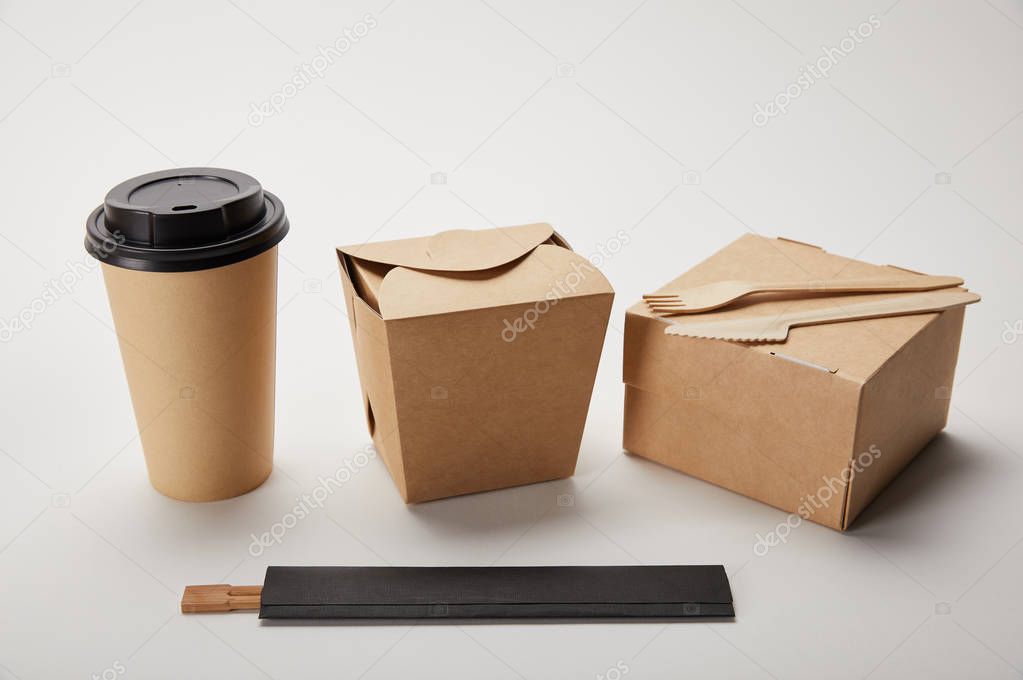 close up view of paper coffee cup, food boxes and chopsticks on white 