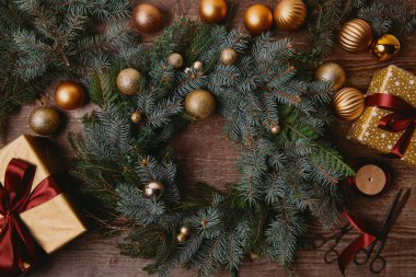 ahşap masa üzerinde Noel hediye kutuları ve köknar çelenk üstten görünüm