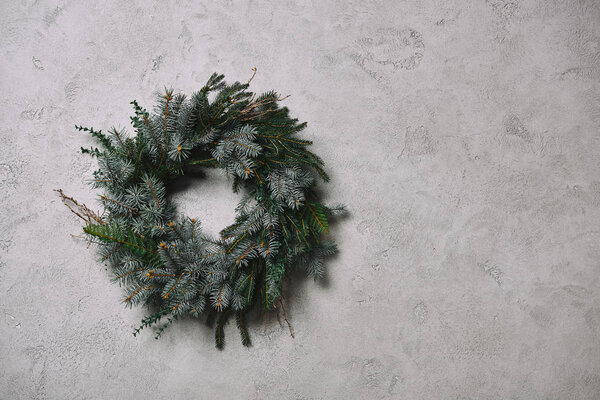 round fir wreath for Christmas decoration hanging on grey wall in room