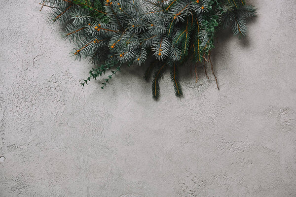 cropped image of fir wreath for Christmas decoration hanging on grey wall in room