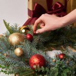 Imagen recortada de niña decorando la corona de abeto de Navidad aislado en blanco