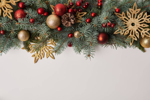 Верхний вид еловых ветвей с рождественскими игрушками и золотыми снежинками, изолированными на белом
