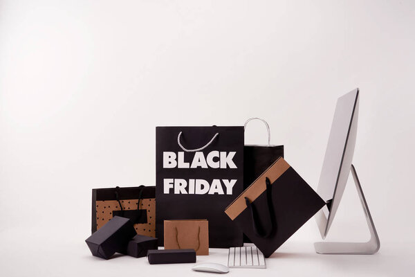 side view of computer and various boxes with shopping bags with black friday sign on white