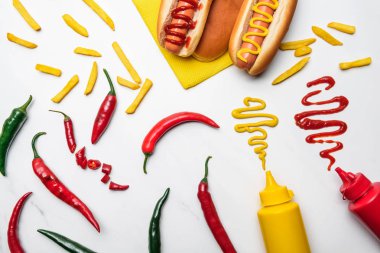 top view of delicious hot dogs and peppers with mustard and ketchup on white marble surface clipart