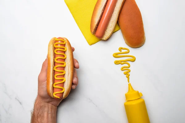 Przycięte Strzał Człowieka Posiadającego Hot Doga Musztardą Białej Powierzchni Marmuru — Zdjęcie stockowe