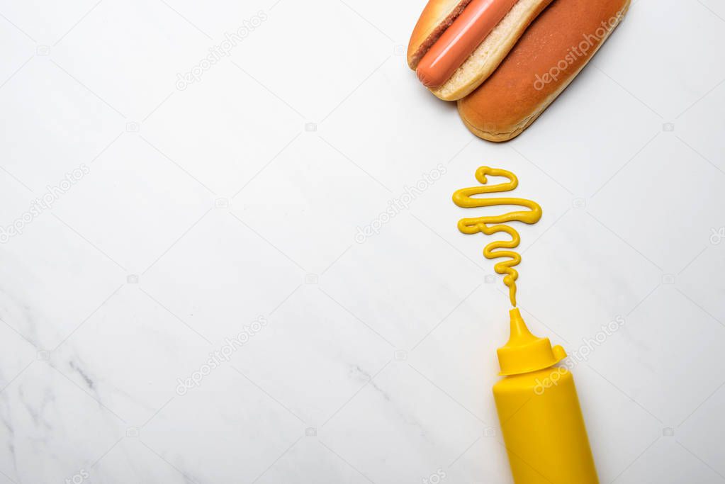 top view of delicious hot dog with mustard on white marble surface