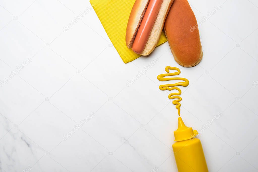 top view of tasty hot dog with mustard on white marble surface