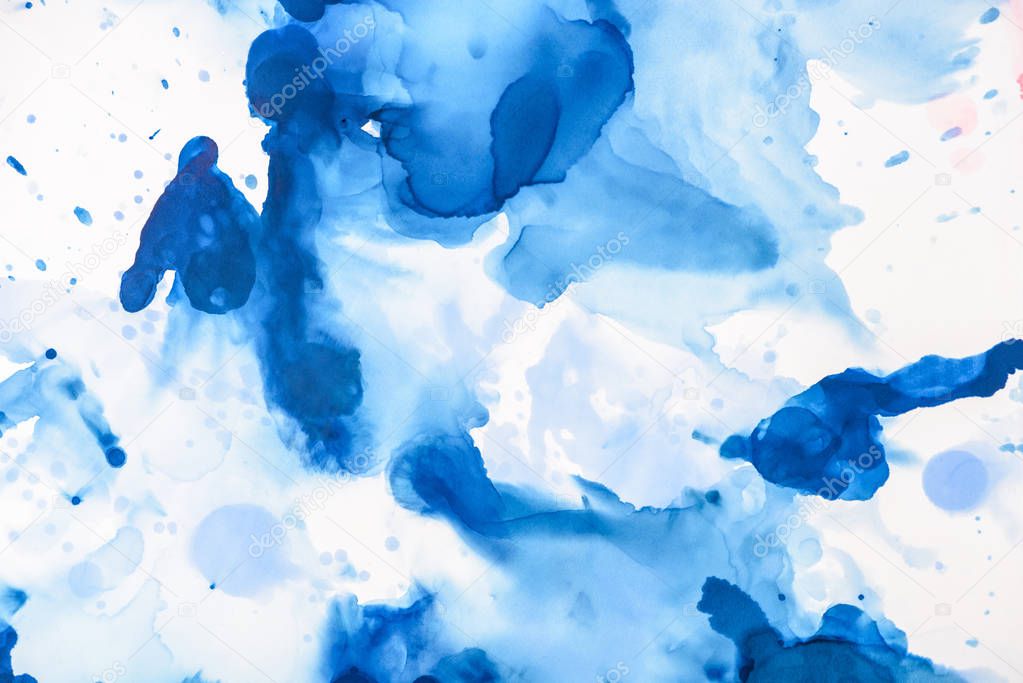 blue splashes of alcohol ink on white as abstract backdrop 