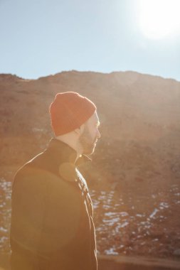 yakışıklı genç adam kırmızı şapka uzakta dağ önünde güneşli gün, Karpatlar, Ukrayna arıyor.