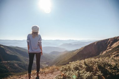 rear view of female traveler looking at mountains on sunny day, Carpathians, Ukraine clipart