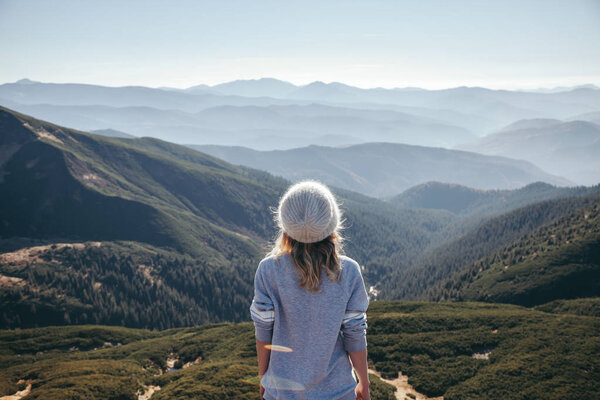 rear view of female traveler looking at scenic mountains on sunny day, Carpathians, Ukraine