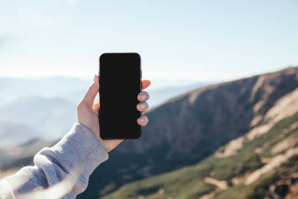 обрезанный снимок женщины, делающей фото горы со смартфоном с пустым экраном, Карпаты, Украина
