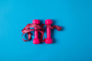 düz lay ile pembe bant ve izole mavi, minimalist kavramı üzerinde halter ölçme 